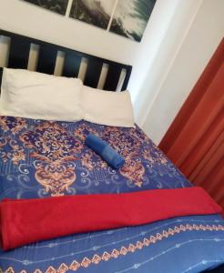 a bed with a blue and red blanket and white pillows at Room at SM Bicutan with Balcony in Manila