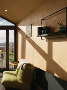 a living room with a green couch and a window at Oaklane Glamping Cabins in Kenmare