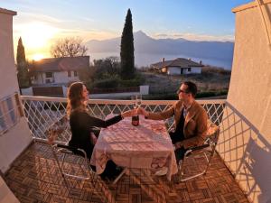 een man en een vrouw aan een tafel op een balkon bij Garda Panoramic House in Albisano