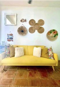 a yellow couch in a room with a wall with plates at CasaDePlaya Cabarete Beachfront in Cabarete