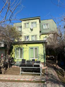 una casa verde con un banco delante en Anisa- Hostel, en Dushanbe