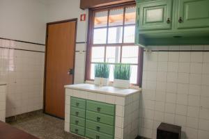a kitchen with green cabinets and a window at Casa De Quintãs in Vila Real