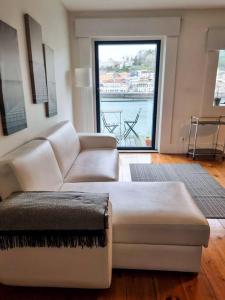 a living room with a couch and a large window at Central duplex apartment-full view of Douro river in Vila Nova de Gaia