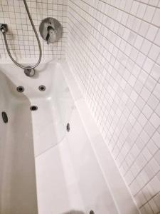 a white tub in a white tiled bathroom at Central duplex apartment-full view of Douro river in Vila Nova de Gaia