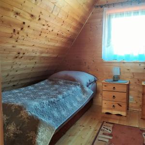 a bedroom in a log cabin with a bed and a window at Domki Letniskowe Neptun in Chłopy