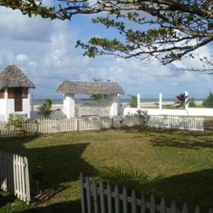 a white fence in a yard with a gazebo at Bungalow le Charme, au bord de la mer 