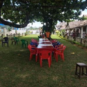 a group of tables and chairs under a tree at Bungalow le Charme, au bord de la mer 