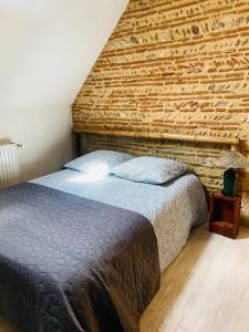 1 cama en un dormitorio con pared de ladrillo en Maison de vacances tout confort, piscine privée & équipements uniques, DORDOGNE, en Lamonzie-Saint-Martin