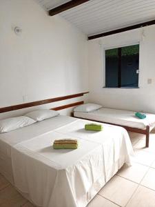 a bedroom with two beds with white sheets and a window at Bimba Chalés Pé na Areia - Guaibim-Ba in Guaibim