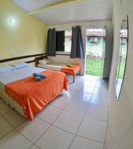 a bedroom with a bed with an orange blanket at Bimba Chalés Pé na Areia - Guaibim-Ba in Guaibim