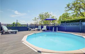 a swimming pool with chairs and an umbrella on a deck at Amazing Home In Douzillac With 4 Bedrooms And Outdoor Swimming Pool in Douzillac