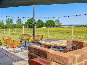 eine Terrasse mit einem Tisch, Stühlen und einem Feld in der Unterkunft The Goat Shed in Hadlow