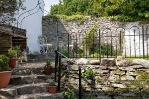 a stone wall with a gate and some plants at Cosy Town-Centre Cottage, St Austell, Cornwall in St Austell