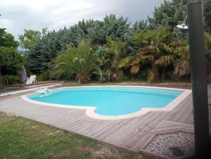 uma piscina com um deque de madeira em redor em La Canette de Phil - Chambre d'hôtes - Hébergement indépendant - vue sur piscine em Samatan