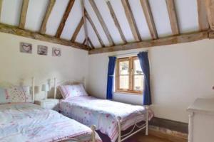 een slaapkamer met 2 bedden en een raam bij Charming Bluebell cottage - lake views nr Tenterden & Rye in Rolvenden