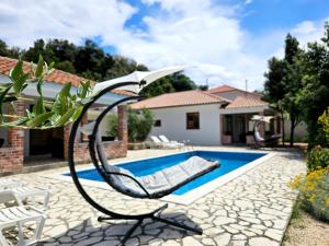 a swimming pool with a chair next to a house at Holiday homes Sintija in Rab