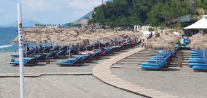 una fila de sillas y sombrillas de paja en una playa en Casa Del Mare Apartment, en Shëngjin