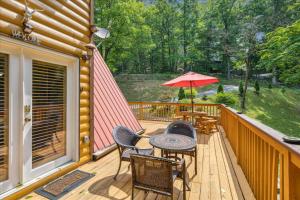 a deck with a table and chairs and an umbrella at Smokey Max Chalet in Sevierville