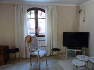 ein Wohnzimmer mit einem TV, einem Stuhl und einem Fenster in der Unterkunft Superbe bas de Villa à 80m de la mer in La Seyne-sur-Mer