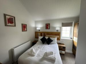 1 dormitorio con 1 cama con sábanas y almohadas blancas en Low Lake Lodge en Reighton