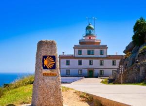 a building with a lighthouse on top of a hill at Pedra de Corvos in Fisterra
