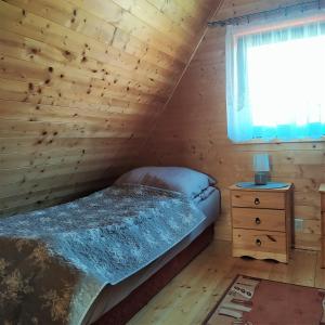 a bedroom with a bed and a window in a log cabin at Domki Letniskowe Neptun in Chłopy