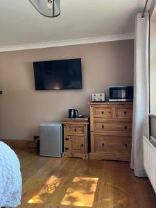 a bedroom with a bed and a dresser and a television at Cherry blossom lodge in Marton