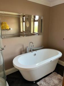 uma banheira branca na casa de banho com um espelho em Cherry blossom lodge em Marton