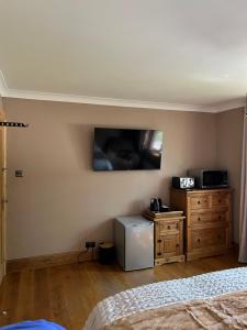 a bedroom with a bed and a tv on the wall at Cherry blossom lodge in Marton