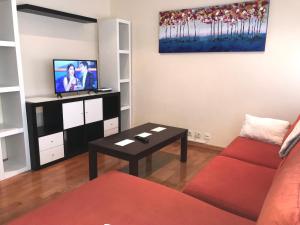 a living room with a red couch and a tv at Casa Nano in Sigüeiro