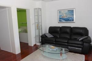 a living room with a black leather couch and a glass table at Holiday House Pine Tree in Nerežišća