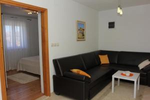 a living room with a black couch and a table at Holiday House Pine Tree in Nerežišća