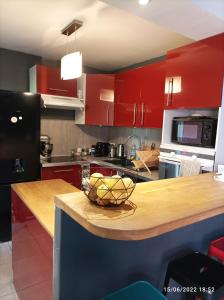 a kitchen with red cabinets and a bowl of fruit on a counter at Maison de vacances, proche de la plage in Fréjus