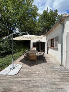 une terrasse avec une table, des chaises et un parasol dans l'établissement Maison dans écrin de verdure vue Sainte-Baume, à Nans-les-Pins