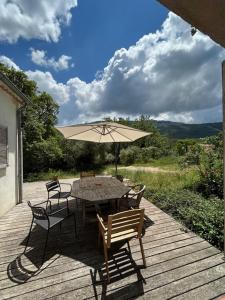une table, des chaises et un parasol sur une terrasse dans l'établissement Maison dans écrin de verdure vue Sainte-Baume, à Nans-les-Pins