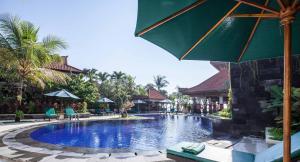 a pool at a resort with chairs and an umbrella at Vila Shanti Beach Front Hotel Sanur in Sanur