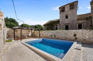 an outdoor swimming pool in front of a stone building at House AnaDora with pool - Zlarin in Zlarin