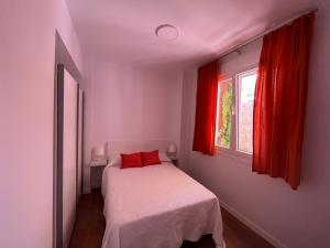 a bedroom with a bed and a window with red curtains at Loreto N1 in Denia