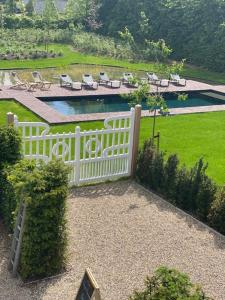 ein weißer Zaun mit Stühlen und ein Pool im Garten in der Unterkunft Villa Copis in Borgloon