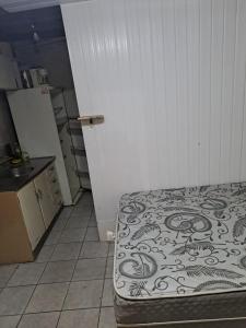 a bedroom with a bed and a kitchen with a refrigerator at Quarto privativo, banheiro externo. in Novo Hamburgo