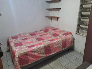 a bed in a room with a quilt on it at Quarto privativo, banheiro externo. in Novo Hamburgo