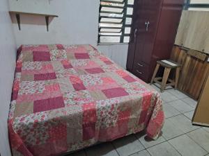 a bedroom with a bed with a quilt on it at Quarto privativo, banheiro externo. in Novo Hamburgo