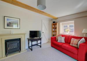 sala de estar con sofá rojo y chimenea en Ruth's en Charminster