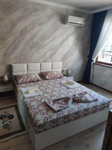 a bedroom with a white bed with a floral bedspread at Apartament Piero in Pomorie