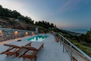 a swimming pool with two picnic tables and the ocean at Villa Koukounaria in Skopelos Town