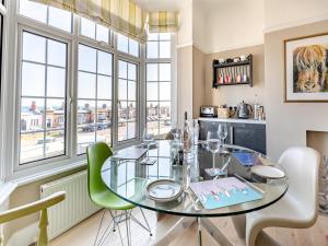 Crossways Mansions في بيكسهيل: غرفة طعام مع طاولة زجاجية وكراسي خضراء