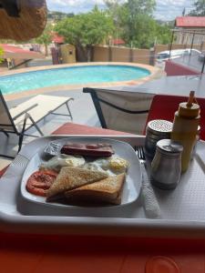 une assiette de nourriture avec des œufs et des saucisses sur une table dans l'établissement Ethithiya Boutique Guesthouse, à Windhoek
