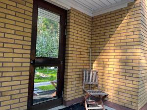 a wooden door and a chair sitting in front of a brick wall at Huoneisto karhujen kaupungissa - Tapanintien Lumo in Ähtäri