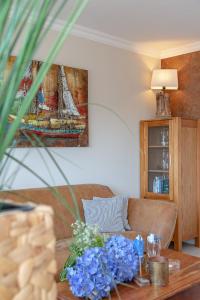 ein Wohnzimmer mit einem Sofa und einem Tisch mit blauen Blumen in der Unterkunft Duen12_45 in Westerland