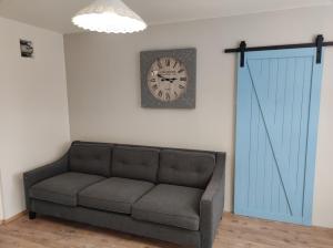 a couch in a room with a clock on the wall at Apartman Šumiac 4 in Šumiac